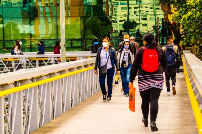 personas caminando por un puente peatonal en Bogotá